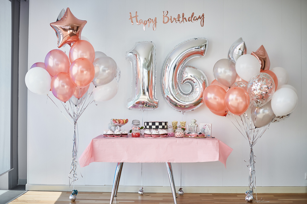 Sweet 16 party decoration with pink and white balloons, 'Happy Birthday 16' sign, and festive table setup. Make her Sweet 16 unforgettable with party rentals in Wilmington, DE.