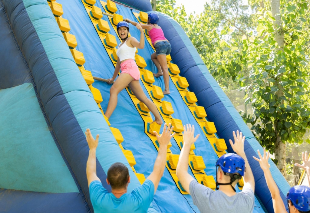 Participants enjoying a team building activity rental with an inflatable climbing wall, ideal for fostering teamwork and collaboration.
