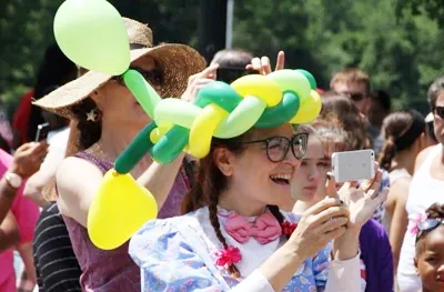 Guests wearing balloon creations made by a balloon artist at a crowded event