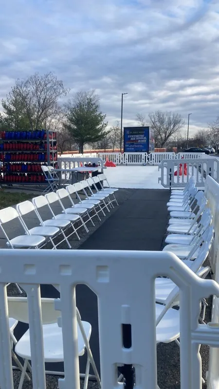 Row of folding chairs set up as a skate changing area beside a synthetic ice rink