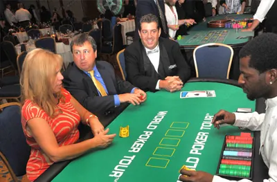 Guests playing Texas Hold Em at a poker table with a dealer and chip tray at a casino night