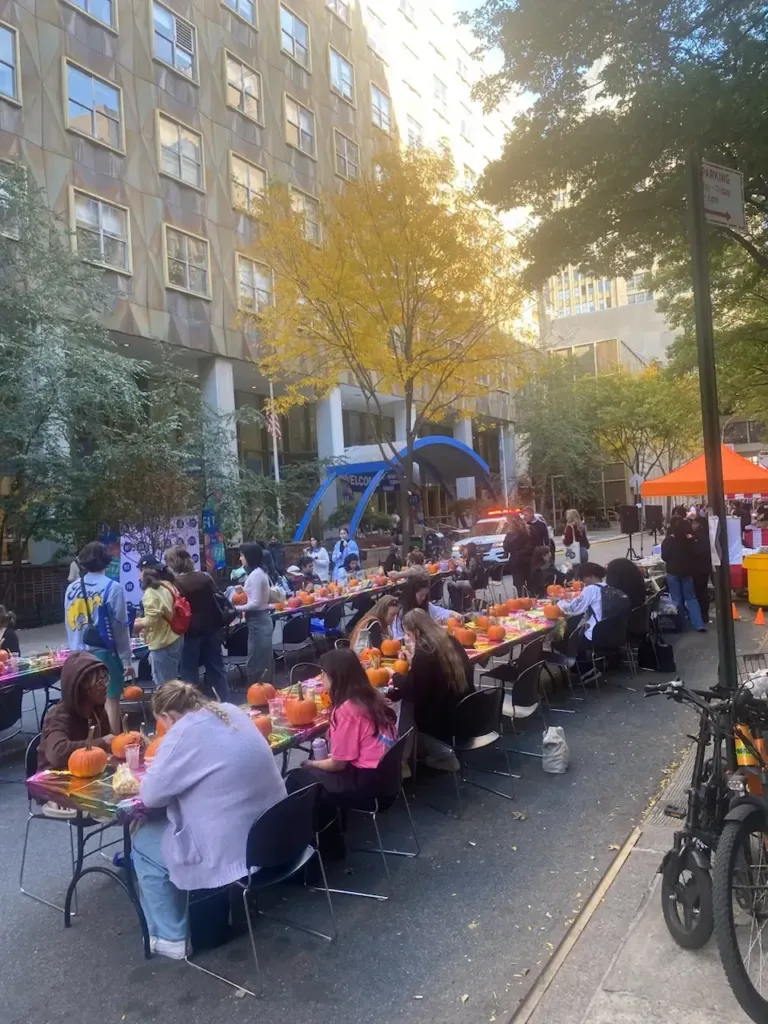 Kids and families painting pumpkins at long tables during an outdoor fall event